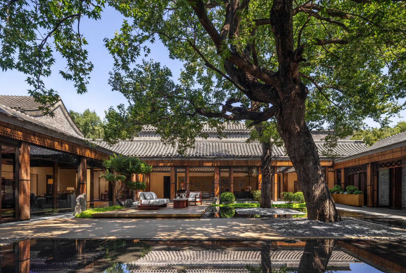 The restored hutong courtyard at Mandarin Oriental Qianmen, Beijing, with a mature tree above grey-tiled roofs