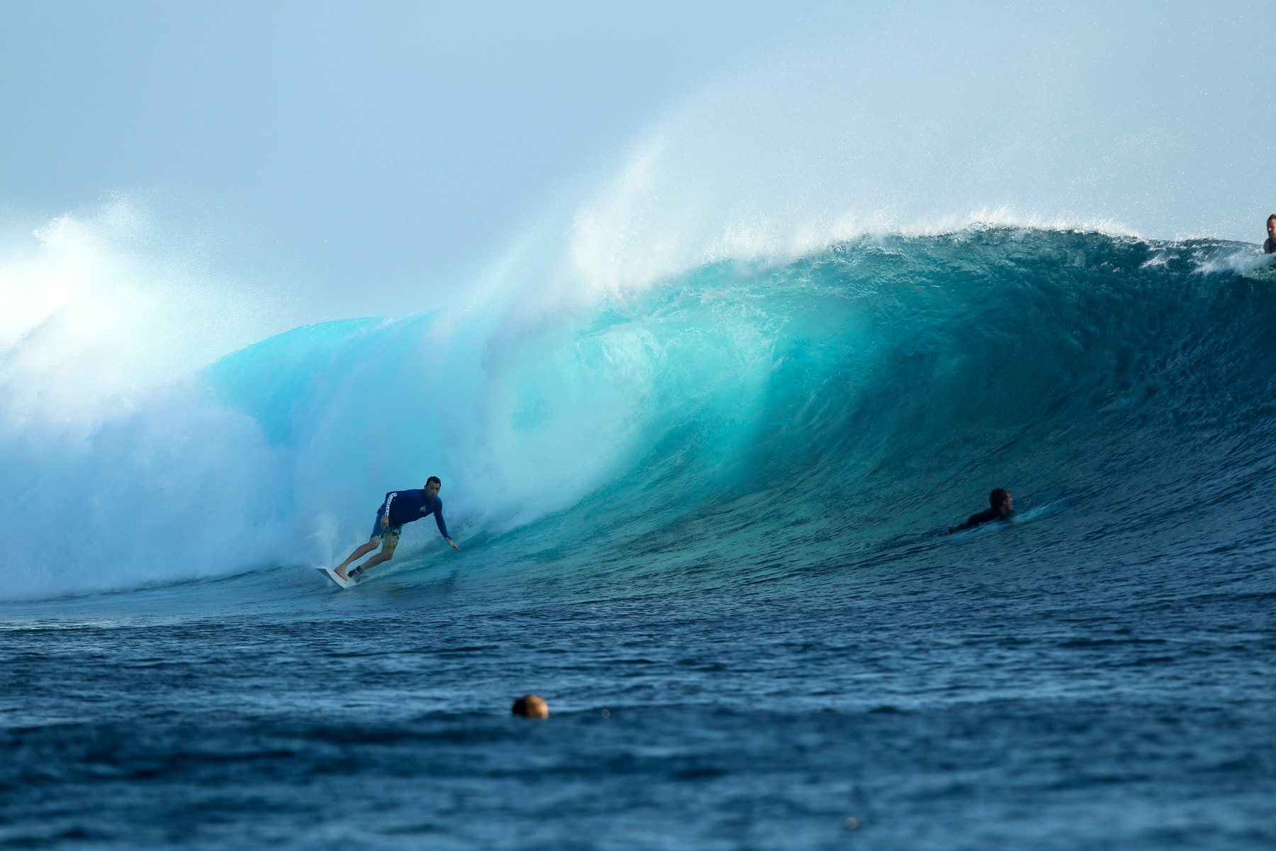 A surfer riding inside a large barrelling wave at Cloudbreak, Fiji