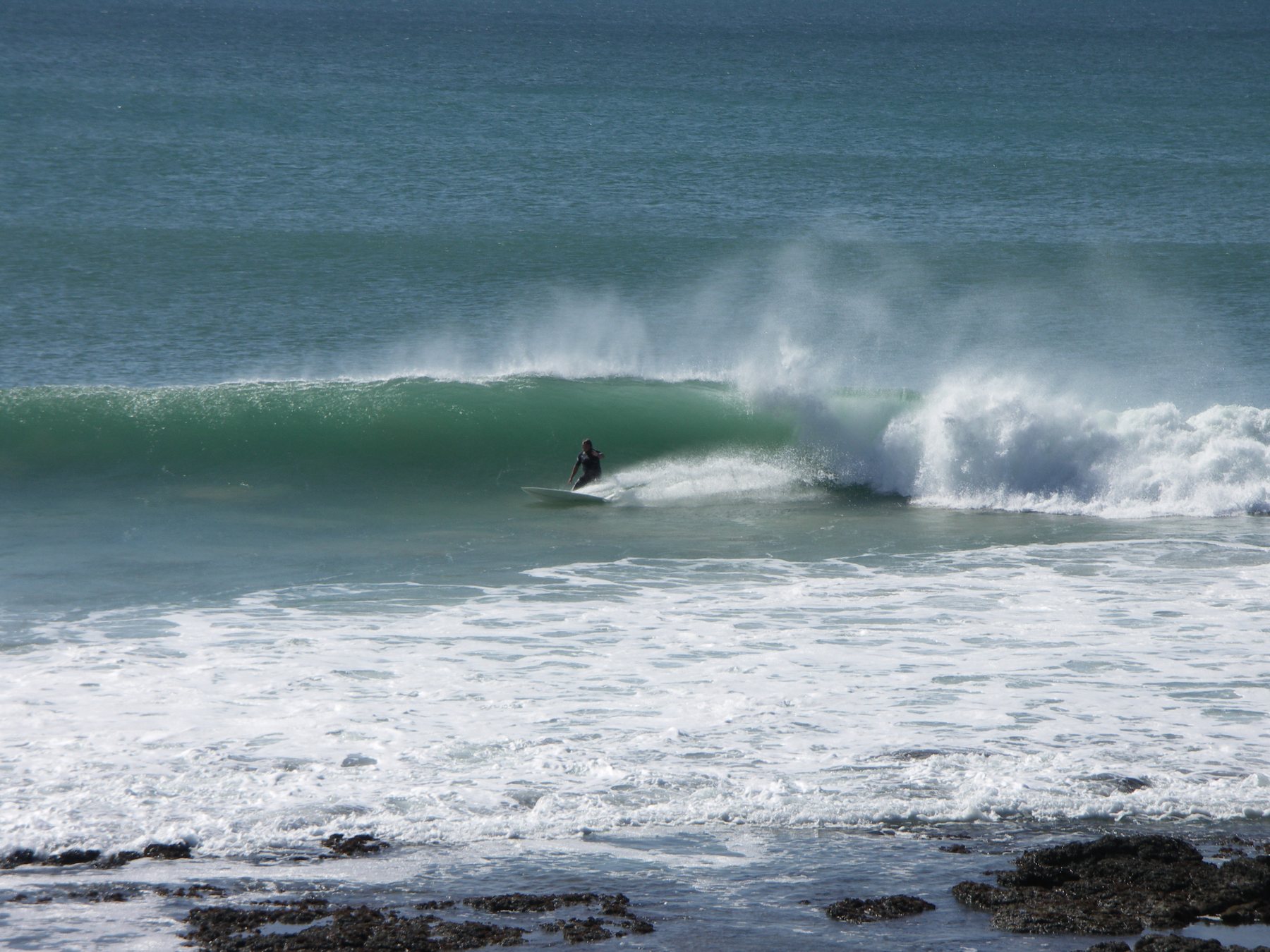A surfer crouched inside a curling wave at Supertubes, Jeffreys Bay
