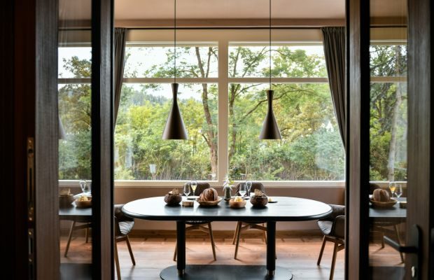 A photograph of the glass-walled villa dining room at Atelier Moessmer Norbert Niederkofler